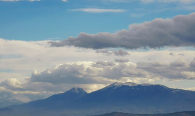 Fototapeta na wymiar Nuvole bianche sopra i monti Appennini in una giornata di sole invernale