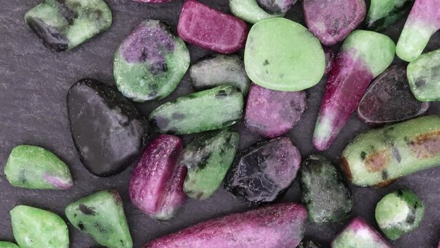Ruby zoisite rare jewel stones texture on black stone background. Moving right seamless loop backdrop.