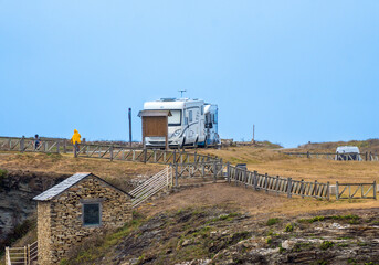 Motorhome parked on top of a hill on the coast of Asturias with stone houses and rural roads below