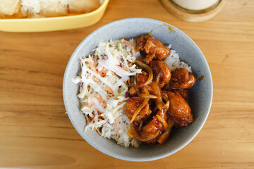 Rice and chicken cooked with soya ketchup sauce served with vegetables salad on bowl