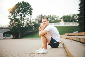 young man talking on a mobile phone, sitting on the steps in the