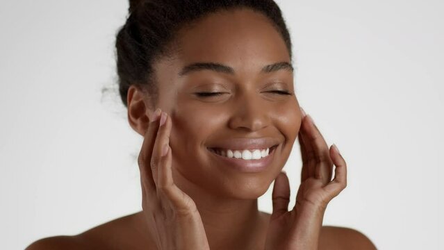 Face yoga concept. Young happy african american woman massaging her face and smiling aside, white background