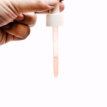 hand hold a spuit medicine pipette with liquid inside isolated white, eyedropper or transparent glass pipette, dropper for eyes and nose