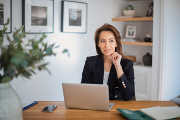 Attractive woman sitting at table and using laptop while working from home