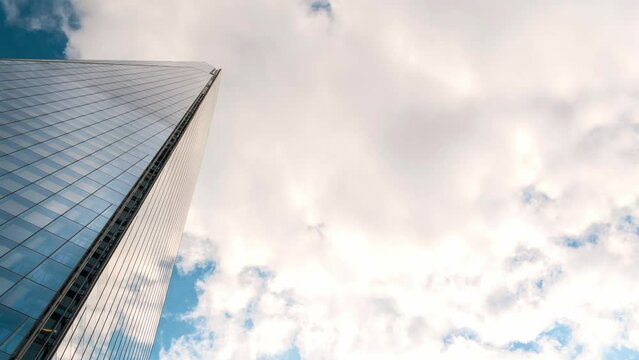 London glass skyscraper on Sky background. Large building in the Blue sky. Big City life landscape. Timelapse of flying moving curly fluffy clouds in sunny day. Nature, Daytime. Meteorology topic