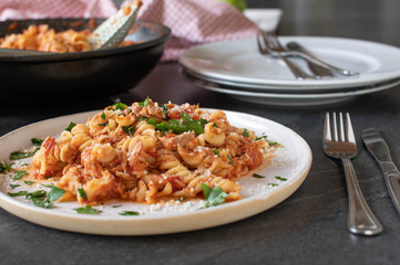 Pasta with tuna, tomato sauce and parmesan cheese on a plate on kitchen table background