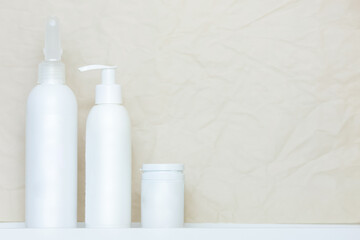 White cosmetic tubes and bottles on light beige backgroundwith copy space