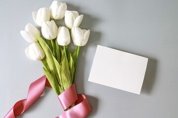 white blank card, white tulip flower on  grey background , top view