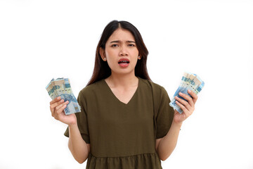 Confused young asian woman standing while holding Indonesian banknotes, Isolated on white background
