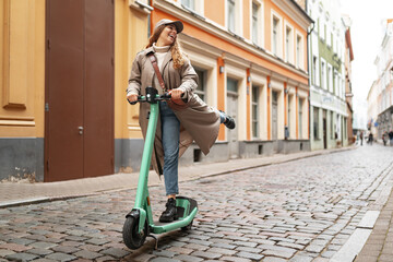 Young blonde woman riding a kick scooter in city street © fotofabrika