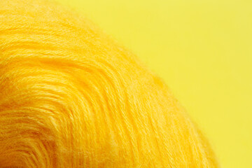 Yellow woolen roll of yarn for knitting on a yellow background. 