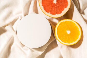 Mockup flat lay circle white podium with orange and grapefruit slices. Top view blank for cosmetics product presentation.
