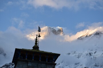Low angle of the Kedarnath temple with the Garhwal Himalayas snow peaks in clouds in the background