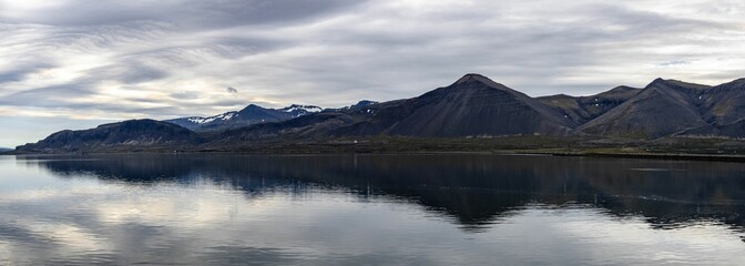 Panoramic view of sea and mountain under cloudy sky in Iceland