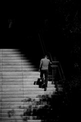 Vertical shot of a man climbing up the stairs in grayscale