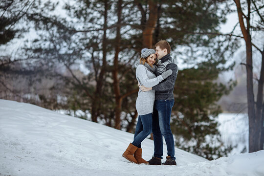 The couple hugs and smiles while standing in the snow.