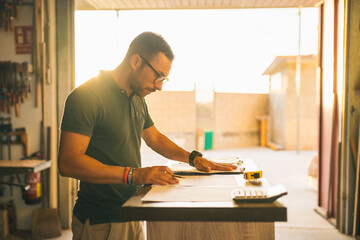 Focused craftsman counting expenses in joinery workshop