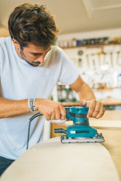 Male worker sanding wood in industry