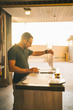 Focused craftsman counting expenses in joinery workshop