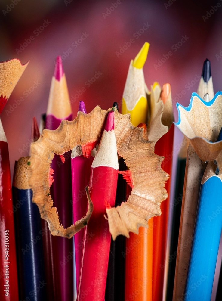 Poster vertical selective focus on colorful sharpened pencils on a red background