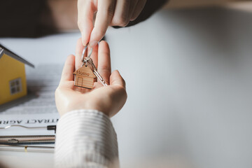 Obraz premium A home rental company employee is handing the house keys to a customer who has agreed to sign a rental contract, explaining the details and terms of the rental. Home and real estate rental ideas.