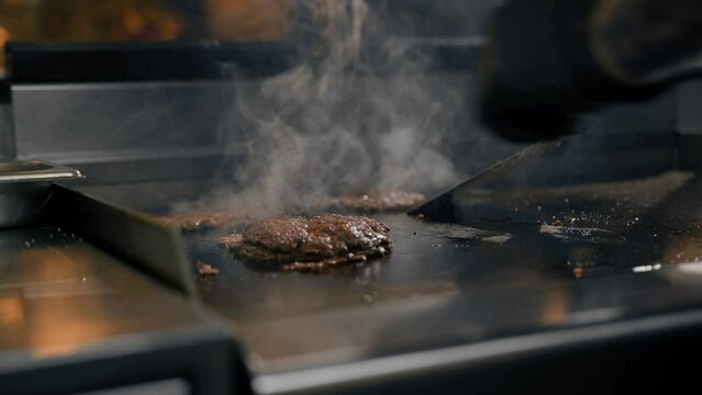 The chef in the kitchen of the restaurant makes cutlets for burgers - smash burger beefsteak