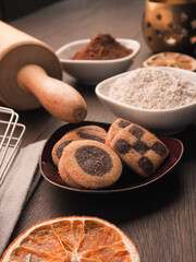 Black and white Christmas cookies on a wooden kitchen table with baking utensils