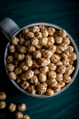 Roasted spicy chickpeas. Roasted chickpeas in a porcelain cup on wooden white background