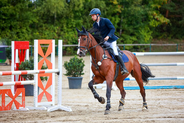Horse jumping horse with rider in the course at a tournament with rider galloping between two...