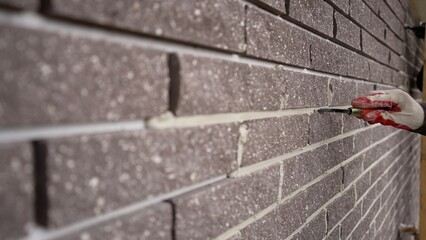 Grouting seams on the facade of the building with a trowel. Plasterers repair the facade of the...