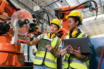 Female automation engineers in safety vest with yellow helmet using laptop for inspection new...