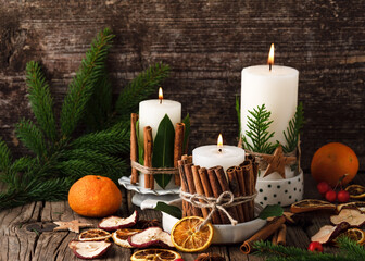 Burning Christmas or advent candles decorated with natural material. Slices of fresh dried apple,...