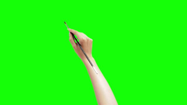 Artist's hand pretending to draw something with a brush over the green screen