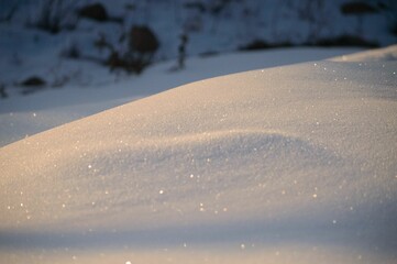 Selective focus small glittering mound of fresh snow in the early morning golden hour light Colorado