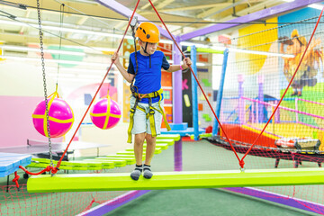 Boy in protective gear holding safety rope and passing obstacle course
