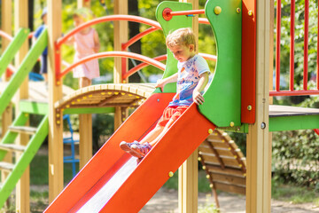 Active kid on colorful slide. Child playing on outdoor playground