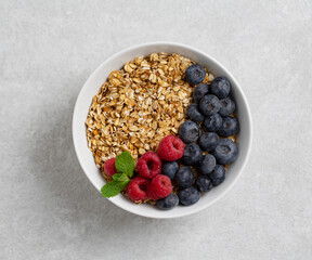 Granola with fresh raspberries and blueberries on table, top view. Healthy food, breakfast.