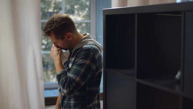 Sick man sneezing in paper napkin at home. Realtime