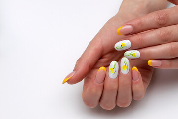French yellow and white manicure with painted yellow tulips on long oval nails close-up on the...