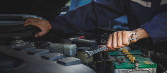 Auto mechanic working on car engine in mechanics garage. Repair service.