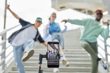 Close up of hip hop dance crew filming video for social media outdoors, focus on smartphone screen,...