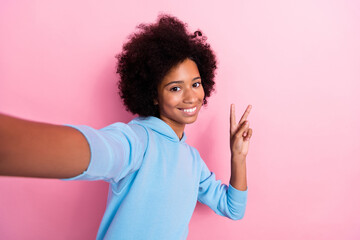 Photo portrait of adorable school girl selfie showing fingers v-sign dressed stylish blue garment isolated on pink color background