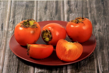 Fresh persimmon fruit on plate. Persimmon fruit Old board background