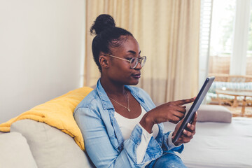 Shot of an attractive young woman using a digital tablet while relaxing at home. Relaxed young...
