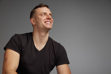 Obraz premium Portrait of young man posing in brown T-shirt, casual clothes isolated over grey studio background. Cheerfully smiling. Concept of fashion and lifestyle