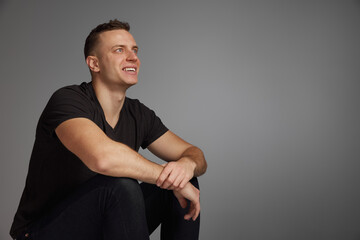 Portrait of young man posing in brown T-shirt, casual clothes isolated over grey studio background. Concept of fashion and lifestyle