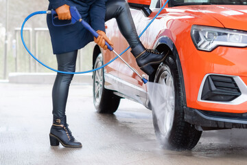 Close up of woman washing the car with high pressure water at self service car wash.