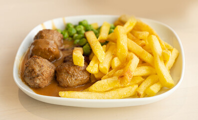 Meatballs with French Fries, Green Peas, Bechamel Sauce, Meat Balls on White Plate Closeup