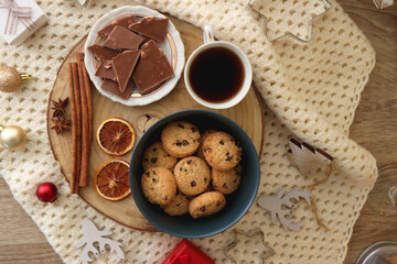 Various Christmas decorations, cup of tea or coffee, sweets, small presents, knitted blanket and candles. Flat lay.