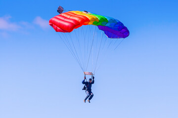 Man gliding down on a parachute in blue sky - 546324204